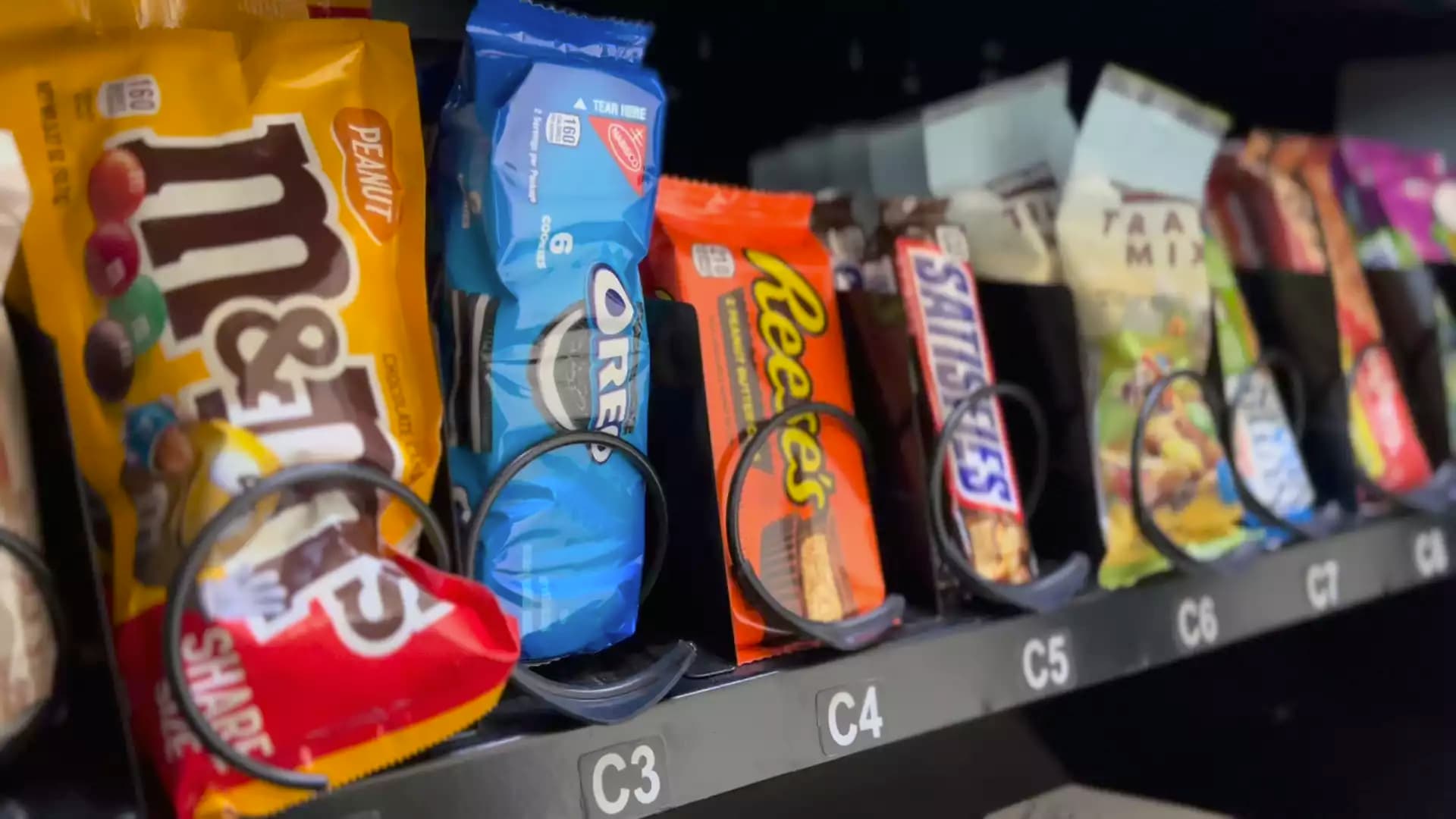 Candy and snack packages stocked behind vending coils